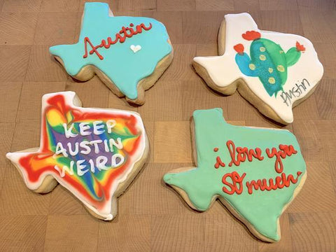 Four texas shaped shortbread cookies with frosting and Austin branding